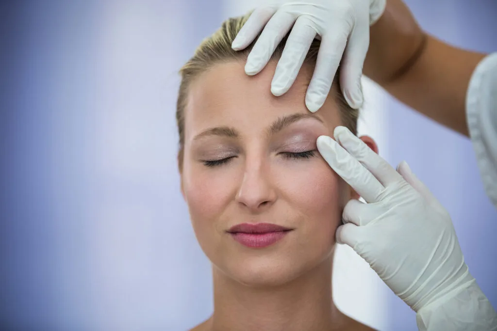 Oftalmóloga examinando los párpados de una paciente durante una consulta de oculoplastia