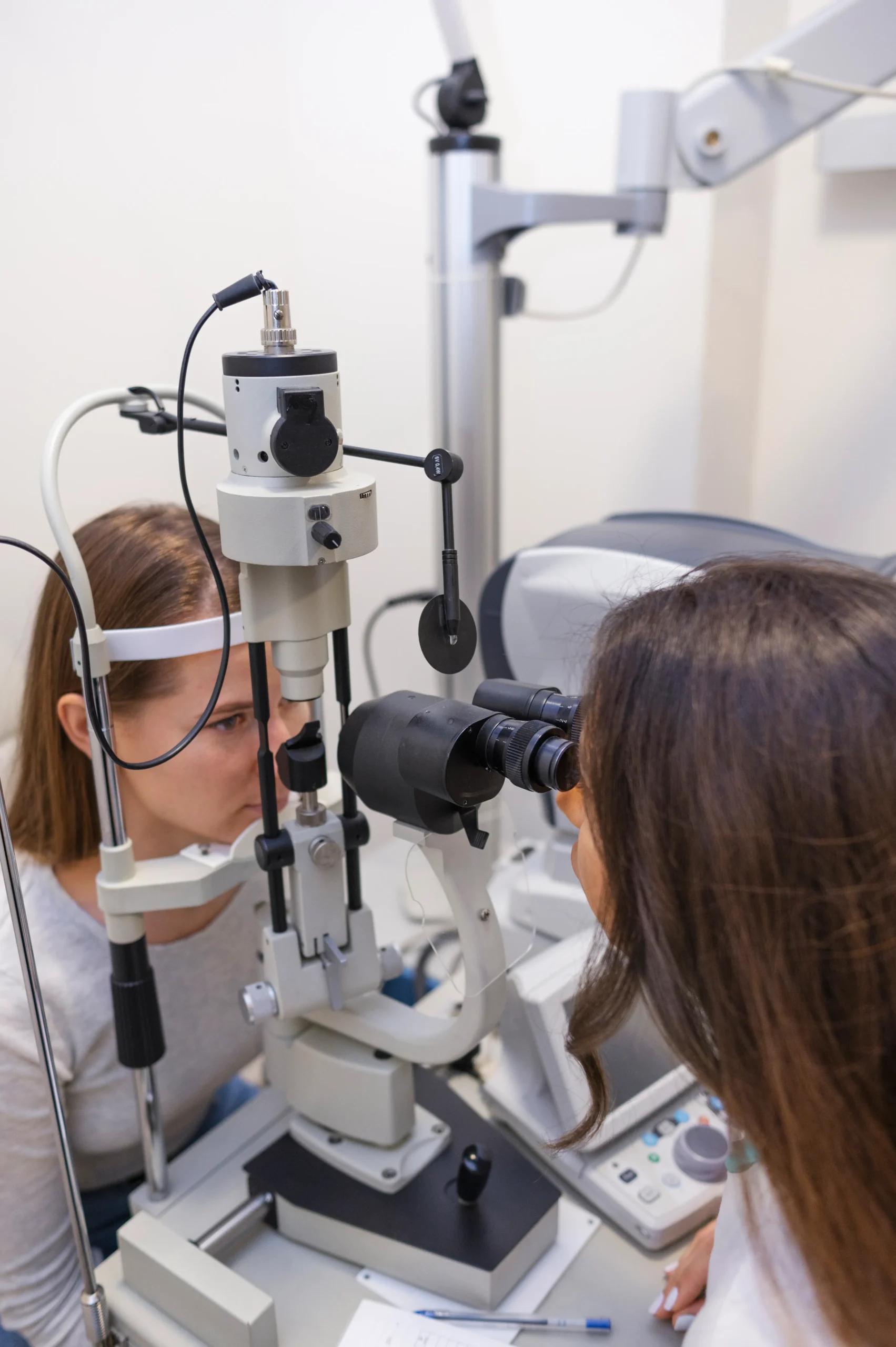 Oftalmóloga examinando la vista de una paciente con una lámpara de hendidura en una consulta médica