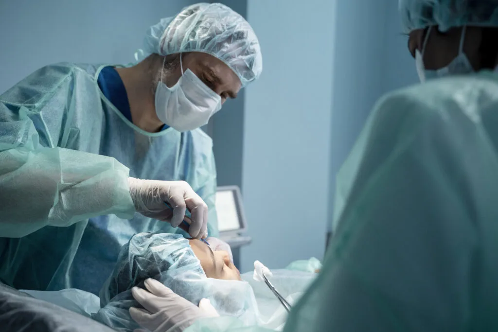 Cirujano con gorro y mascarilla realizando una intervención de cirugía de párpados en un quirófano